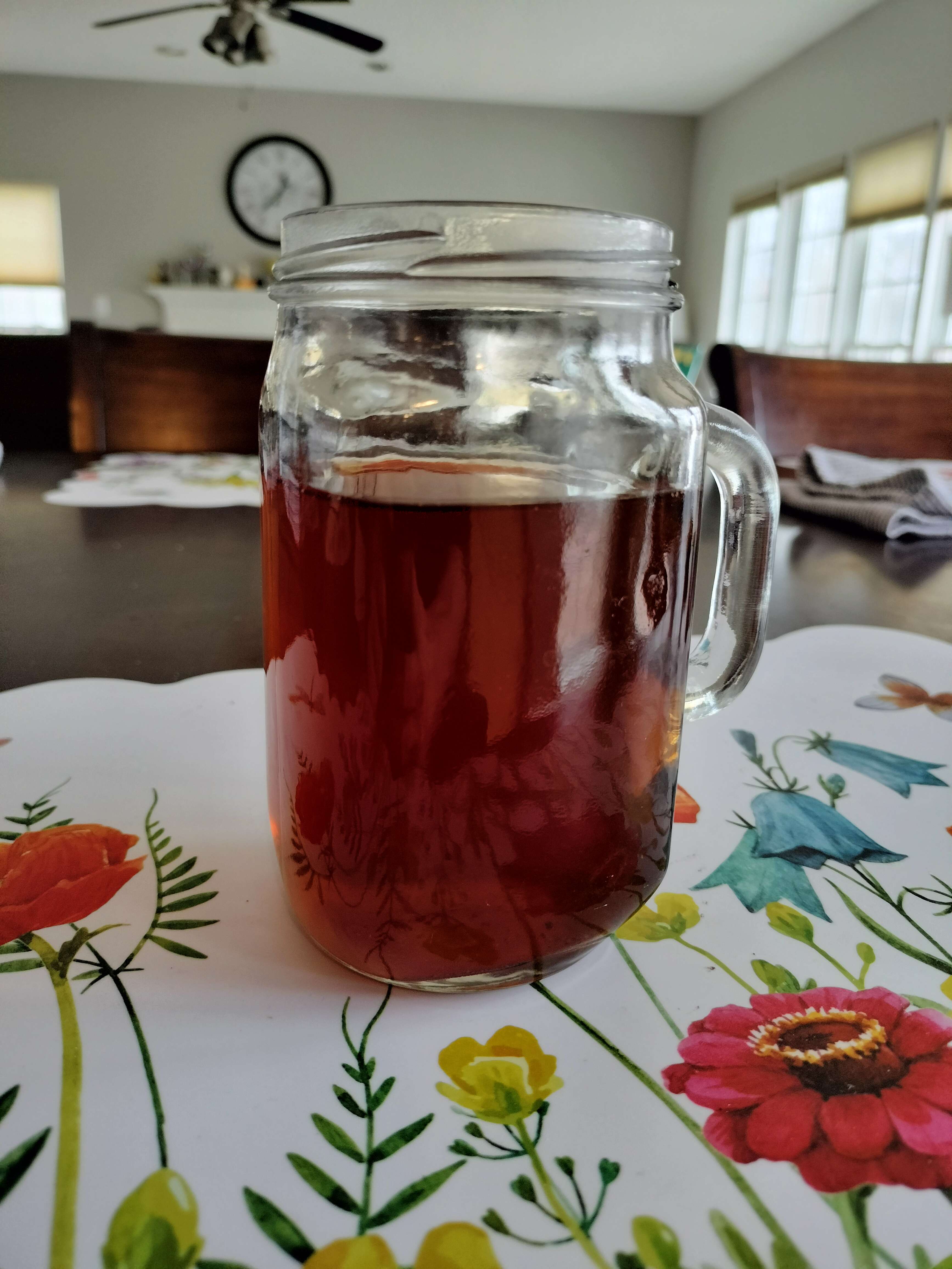 A tall glass mug with a handle on one end, not quite full. The tea is a rich red-brown.